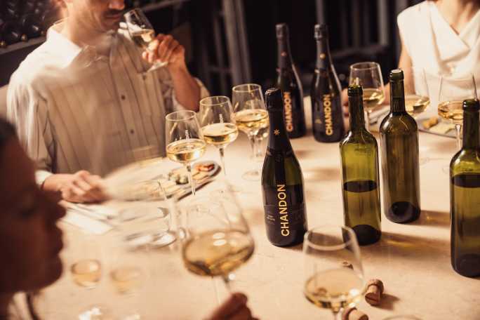 Degustación de CHANDON en Mendoza: gente probando espumantes con botellas de CHANDON Brut y Rosé en la mesa.