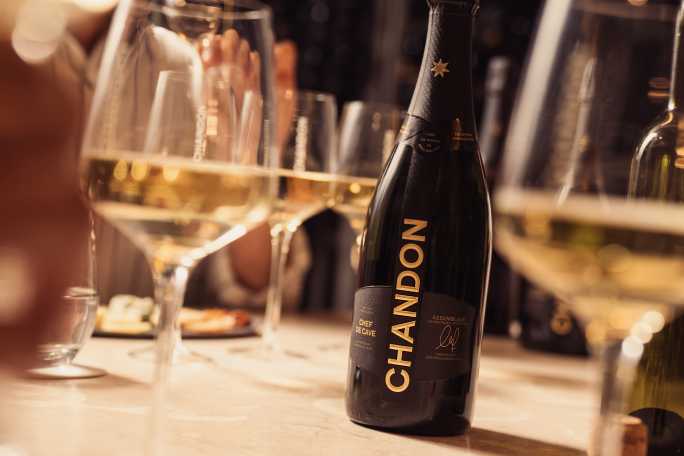 Botella de CHANDON Argentina y copas de vino espumoso en una mesa de mármol durante una degustación en Mendoza.