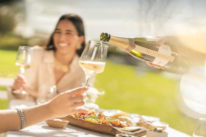Sirviendo Chandon Extra Brut en copas durante un almuerzo al aire libre en Mendoza.