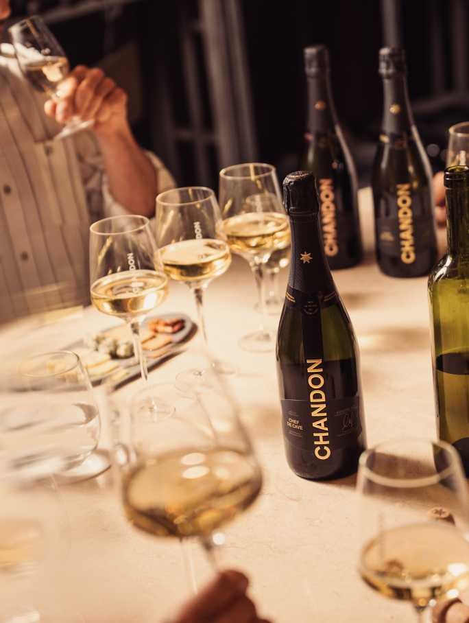 Degustación de CHANDON en Mendoza: gente probando espumantes con botellas de CHANDON Brut y Rosé en la mesa.