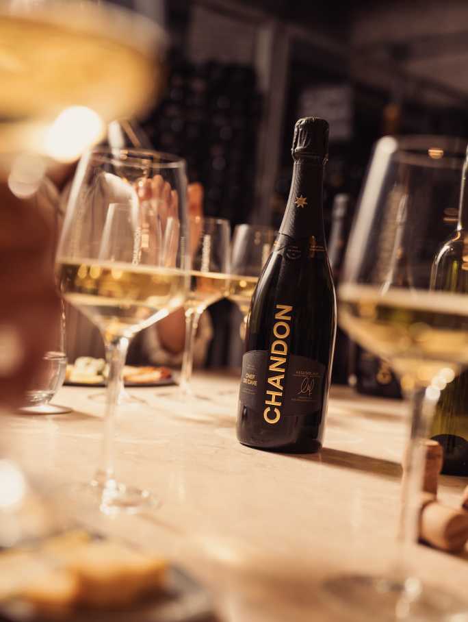 Botella de CHANDON Argentina y copas de vino espumoso en una mesa de mármol durante una degustación en Mendoza.