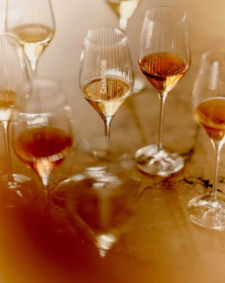Ribbed glasses filled with CHANDON Australia Brut and Rosé sparkling wine catching warm light.