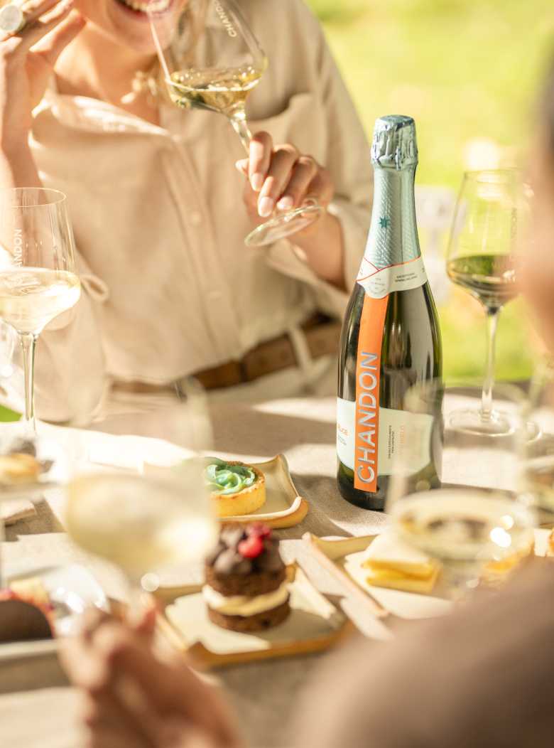 Grupo de personas degusta espumante CHANDON Blanc de Blancs alrededor de una mesa con copas servidas.