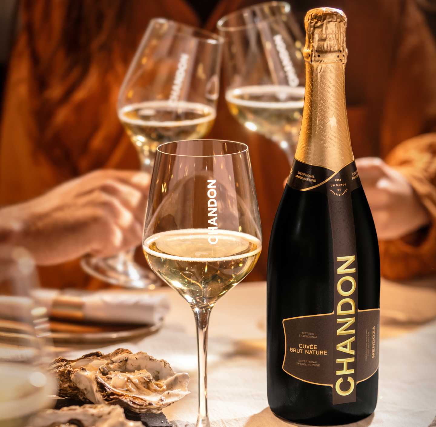 Botella de CHANDON Cuvée Brut Nature Mendoza, copas de vino espumoso y ostras frescas.