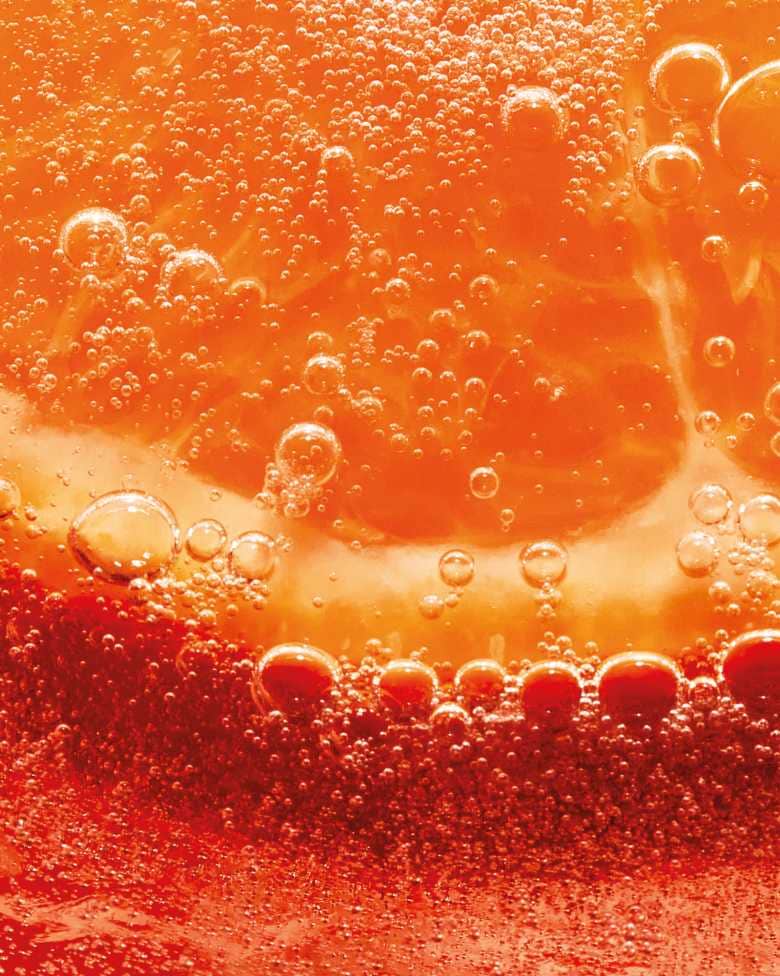 Gros plan d'une tranche d'orange immergée dans un liquide pétillant, de couleur orangée