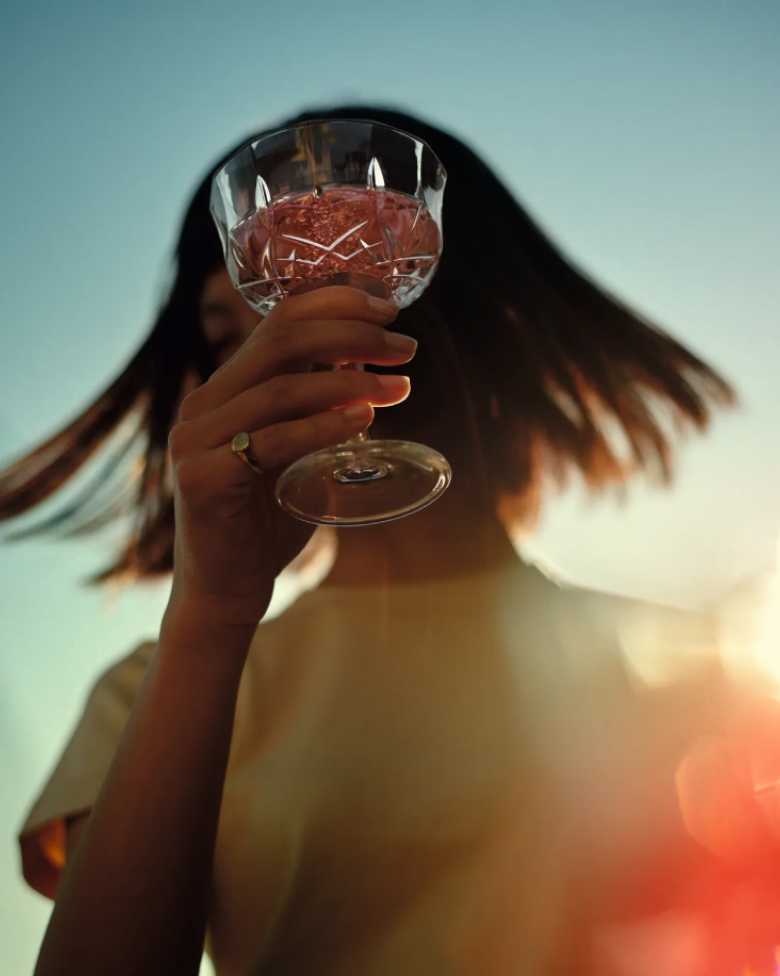 Mujer que levanta su vaso de CHANDON Rosé