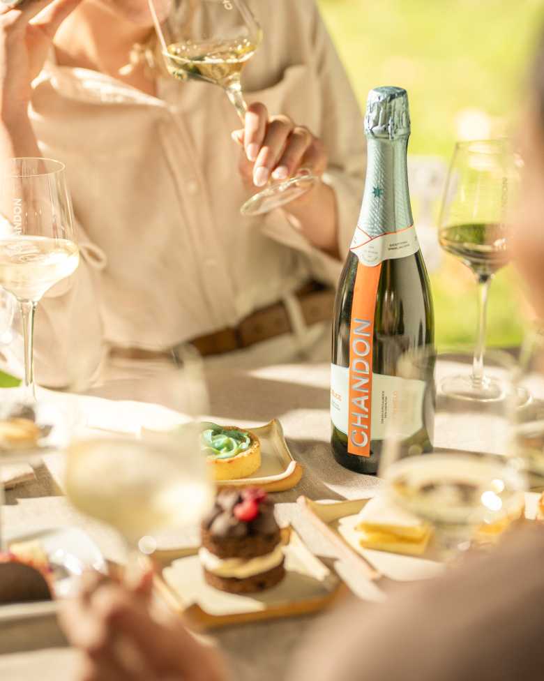 Grupo de personas degusta espumante CHANDON Blanc de Blancs alrededor de una mesa con copas servidas.